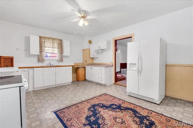 kitchen with white fridge with ice dispenser, range, light flooring, a ceiling fan, and white cabinetry