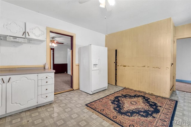 unfurnished bedroom with white fridge with ice dispenser, light floors, wood walls, and ceiling fan