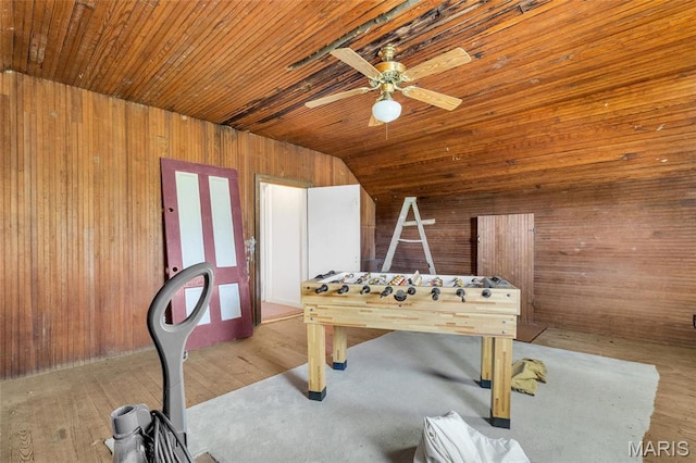 recreation room featuring wooden walls, wood ceiling, a ceiling fan, vaulted ceiling, and wood finished floors