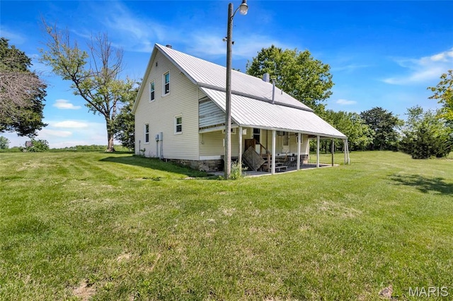 rear view of property featuring a lawn and metal roof
