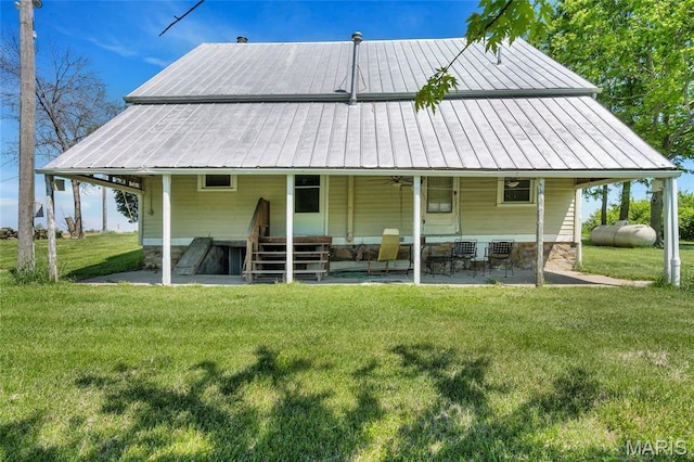 rear view of property with a ceiling fan, a yard, a patio, and metal roof
