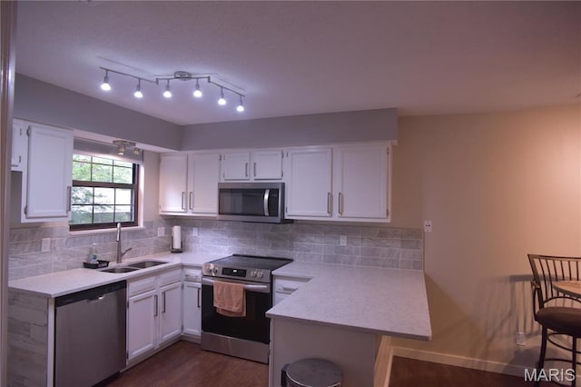 kitchen with appliances with stainless steel finishes, a sink, light countertops, and white cabinetry