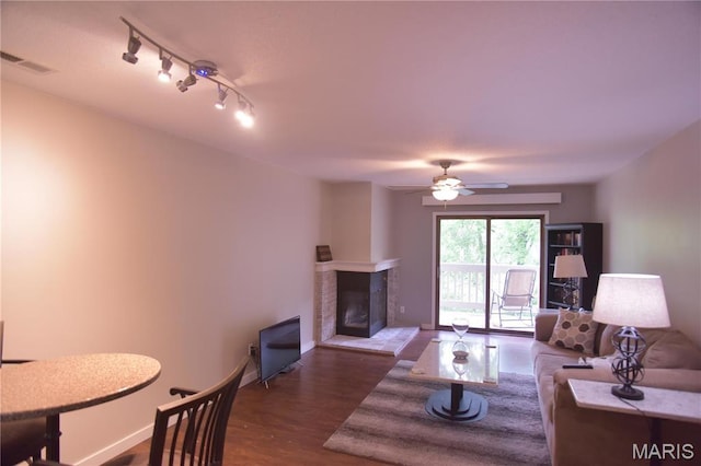 living room featuring baseboards, a ceiling fan, dark wood-style flooring, and a multi sided fireplace