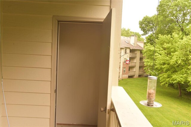 property entrance with a lawn and a balcony