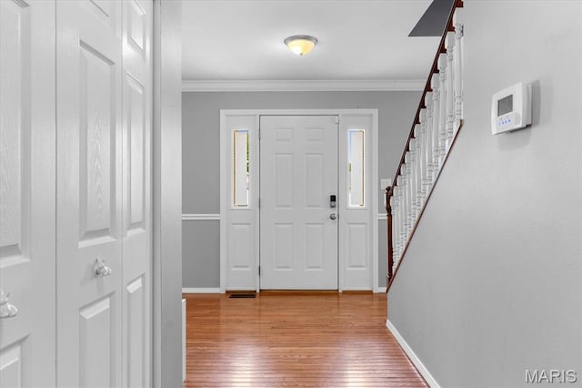 entryway featuring baseboards, stairs, hardwood / wood-style flooring, and crown molding