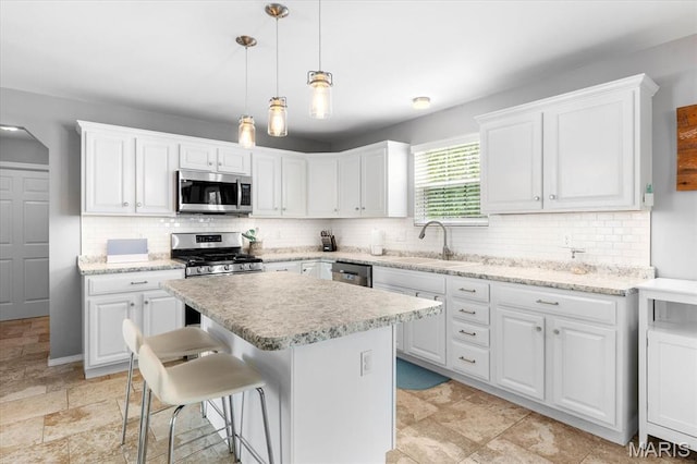 kitchen featuring appliances with stainless steel finishes, a sink, white cabinetry, and decorative backsplash