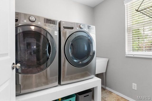 clothes washing area featuring independent washer and dryer and baseboards