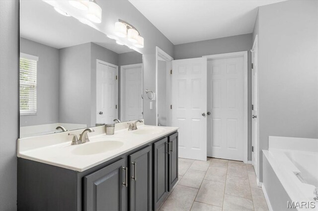full bathroom featuring a bath, double vanity, baseboards, and tile patterned flooring