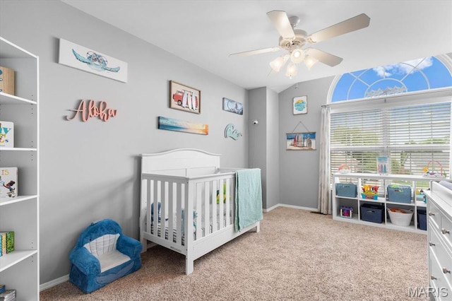 bedroom featuring a nursery area, carpet, a ceiling fan, and baseboards