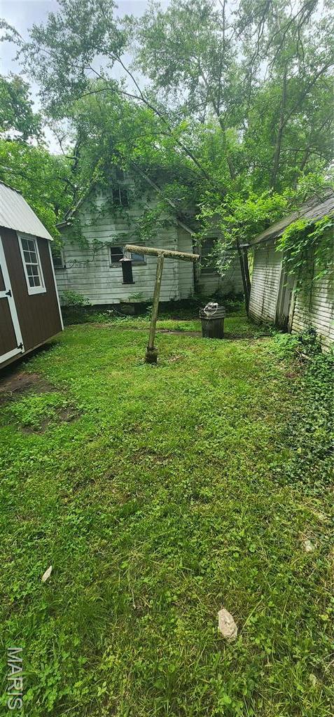 view of grassy yard with a storage shed and an outbuilding