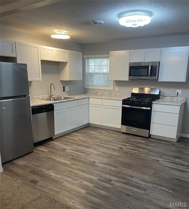 2820 Birch Ave, Granite City, IL 62040 - kitchen featuring appliances with stainless steel finishes, a sink, a textured ceiling, light countertops, and dark wood-style floors