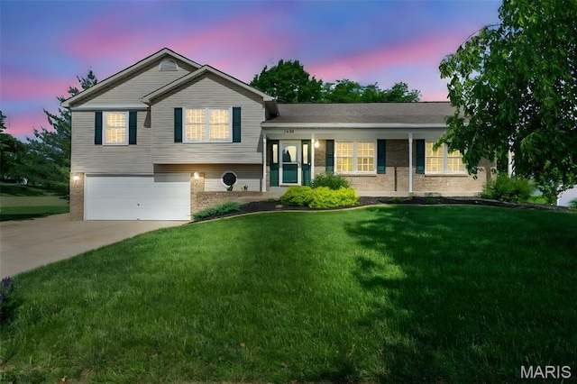 split level home with an attached garage, brick siding, driveway, and a front yard