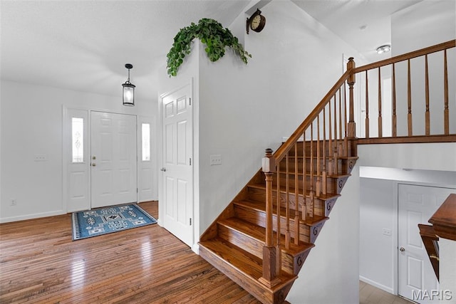 foyer entrance with hardwood / wood-style floors, stairs, and baseboards