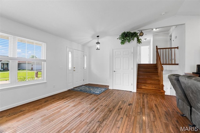 entrance foyer featuring hardwood / wood-style floors, stairs, baseboards, and lofted ceiling
