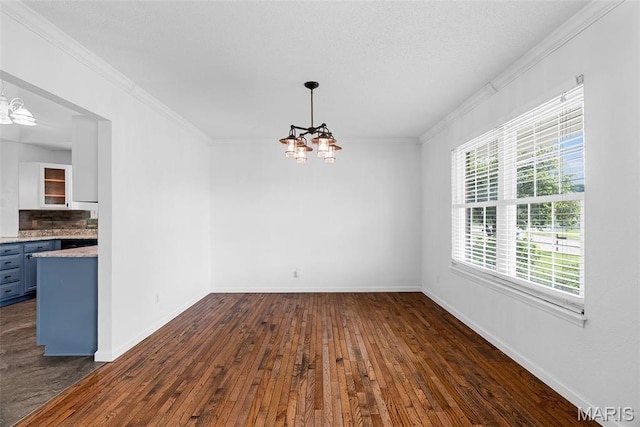 unfurnished dining area featuring a chandelier, dark wood finished floors, ornamental molding, and baseboards