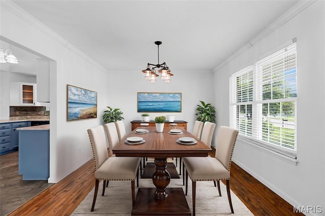 dining space with dark wood-type flooring, a chandelier, crown molding, and baseboards