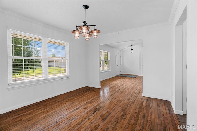 empty room featuring crown molding, a chandelier, wood-type flooring, and baseboards
