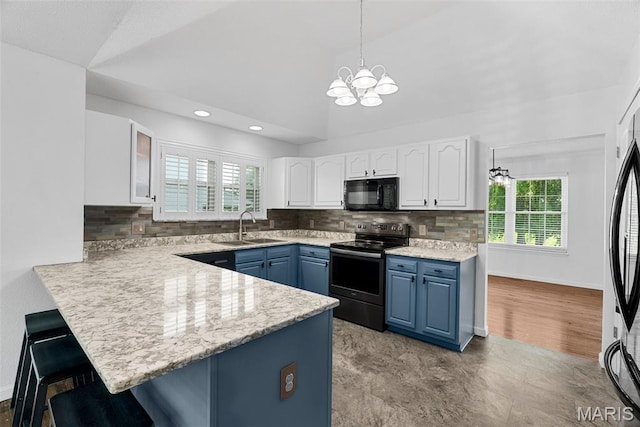 kitchen with electric stove, black microwave, blue cabinetry, a sink, and a breakfast bar