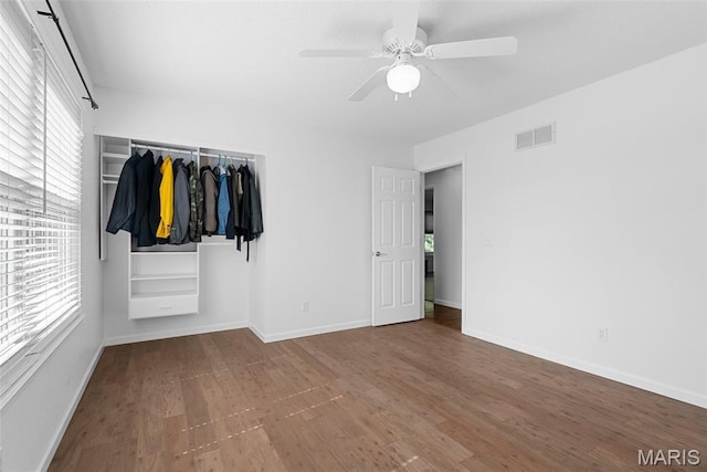 unfurnished bedroom featuring wood finished floors, baseboards, a closet, and a ceiling fan