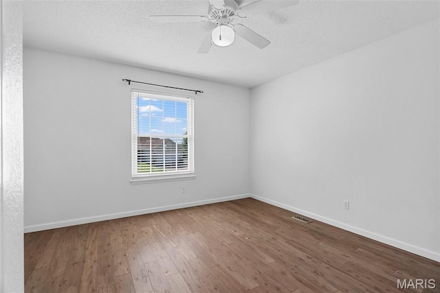 empty room featuring wood finished floors, a textured ceiling, baseboards, and ceiling fan