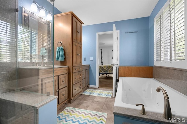 full bath featuring a whirlpool tub, vanity, and tile patterned floors