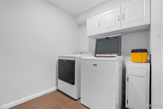 washroom featuring washing machine and dryer, cabinet space, and baseboards