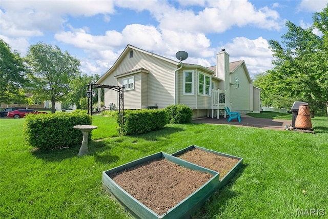rear view of property featuring a vegetable garden, a chimney, and a yard