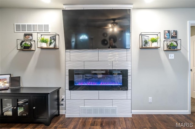 living area featuring a glass covered fireplace, wood finished floors, and baseboards
