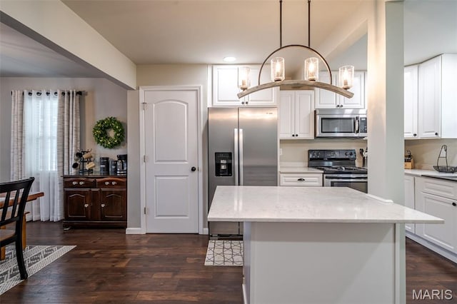 kitchen featuring appliances with stainless steel finishes, dark wood-style floors, light stone countertops, white cabinets, and pendant lighting