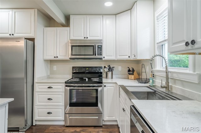 kitchen with stainless steel appliances, a sink, white cabinets, recessed lighting, and dark wood-style flooring