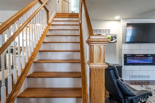 stairway with a fireplace and recessed lighting