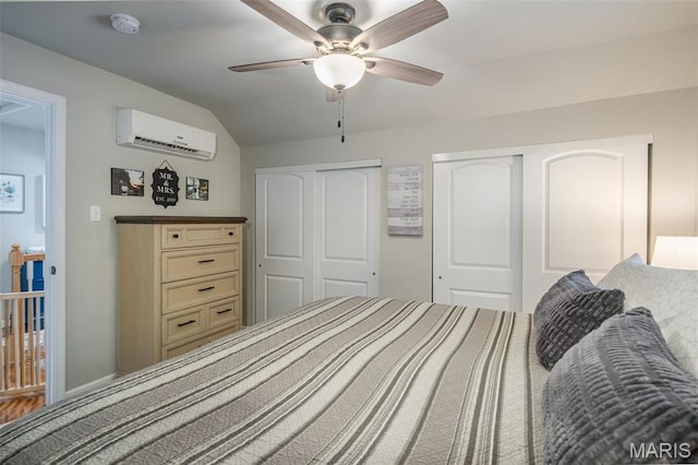 bedroom with a wall unit AC, vaulted ceiling, two closets, and ceiling fan