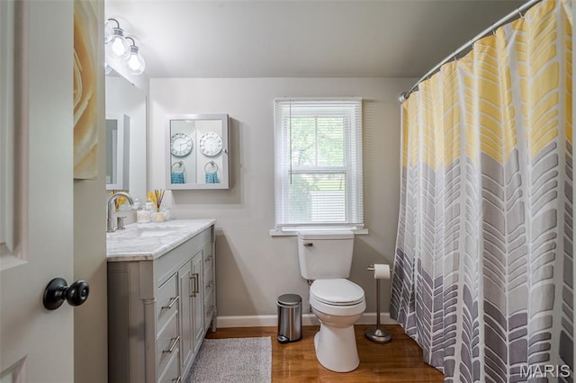 bathroom featuring wood finished floors, toilet, vanity, and baseboards