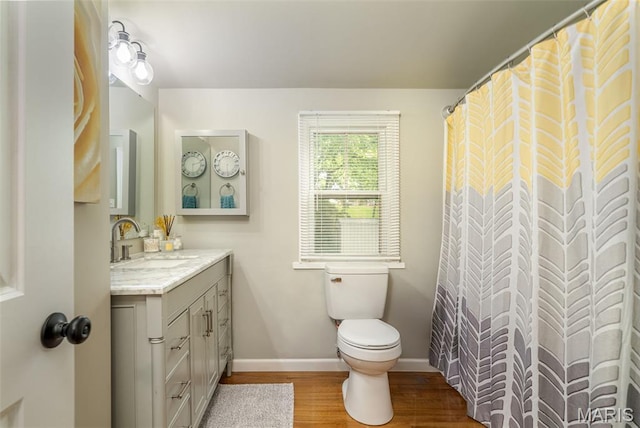 full bathroom featuring wood finished floors, baseboards, toilet, and vanity