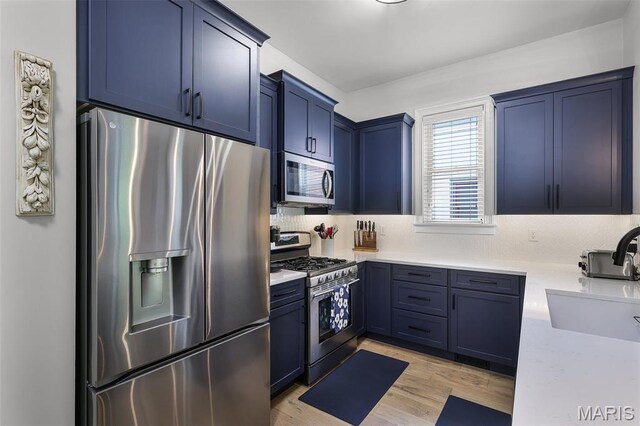 1606 Mississippi Ave, Saint Louis, MO 63104 - kitchen featuring appliances with stainless steel finishes, a sink, light wood-type flooring, and blue cabinetry