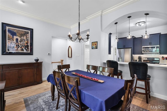 1606 Mississippi Ave, Saint Louis, MO 63104 - dining space featuring light wood-style floors, a chandelier, ornamental molding, and arched walkways