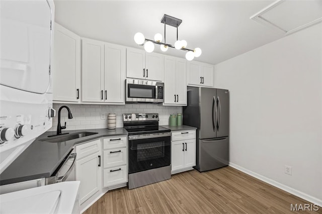 8917 Cardinal Ter, Saint Louis, MO 63144 - kitchen featuring stainless steel appliances, a sink, backsplash, dark countertops, and light wood-type flooring