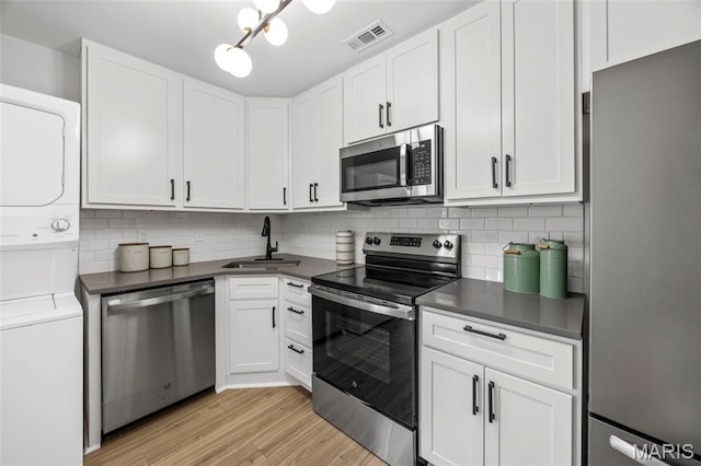 8917 Cardinal Ter, Saint Louis, MO 63144 - kitchen with stainless steel appliances, stacked washing machine and dryer, dark countertops, and a sink