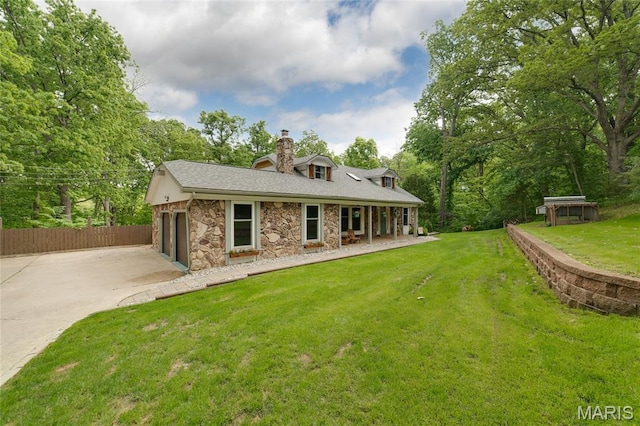 rear view of house featuring stone siding, a chimney, and driveway