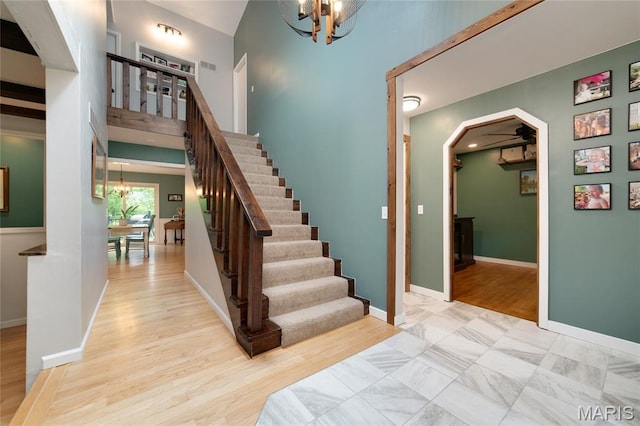 staircase with a chandelier, arched walkways, baseboards, and wood finished floors