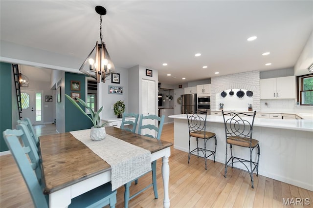 dining area featuring a chandelier, light wood-style floors, recessed lighting, and baseboards