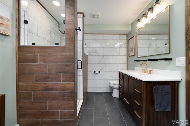 full bathroom featuring tile walls, tile patterned flooring, a shower stall, toilet, and vanity