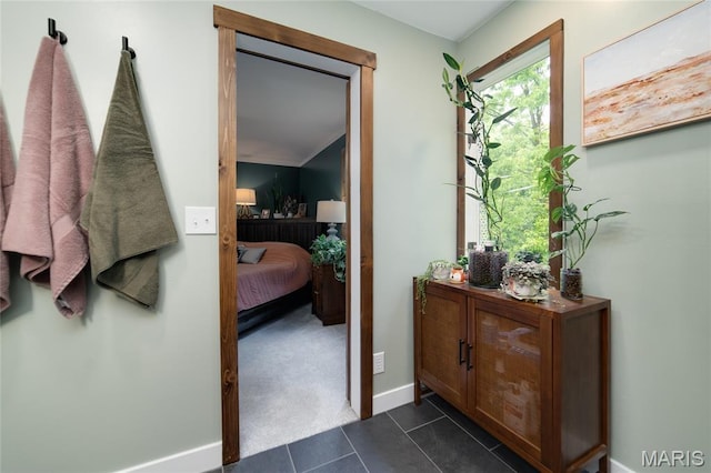doorway featuring baseboards and dark tile patterned flooring