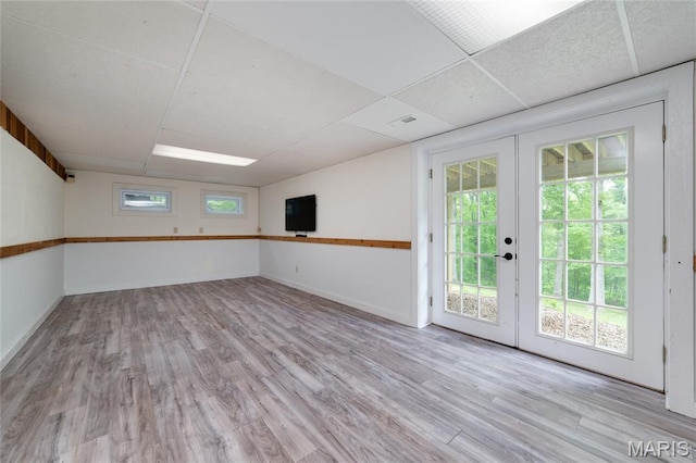 empty room with french doors, light wood-style floors, and baseboards