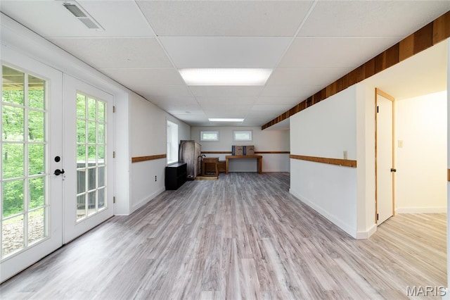 unfurnished office with a drop ceiling, french doors, light wood finished floors, and baseboards