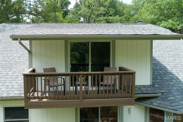 rear view of house with roof with shingles and a balcony