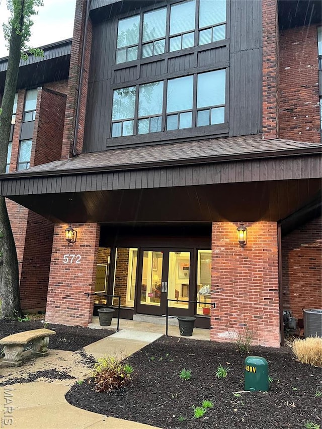 view of exterior entry featuring central air condition unit and brick siding