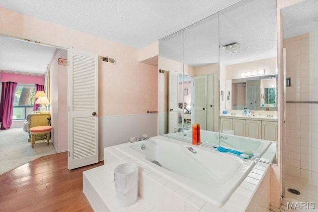 572 Coeur De Royale Dr Unit 105, Saint Louis, MO 63141 - full bath with a textured ceiling, a garden tub, vanity, wood finished floors, and a shower stall