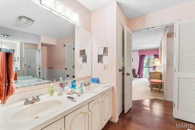 572 Coeur De Royale Dr Unit 105, Saint Louis, MO 63141 - ensuite bathroom with a textured ceiling, double vanity, wood-type flooring, and a shower with shower door