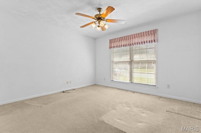 carpeted empty room with baseboards and a ceiling fan